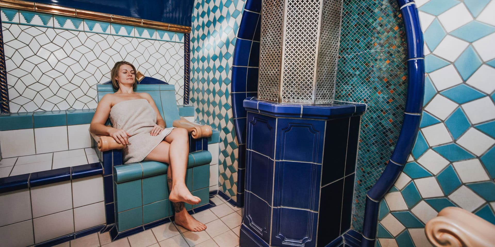 Entspannter Gast im Spa-Bereich des Hotel Panorama in Daun, umgeben von blauen Fliesen und entspannender Atmosphäre.